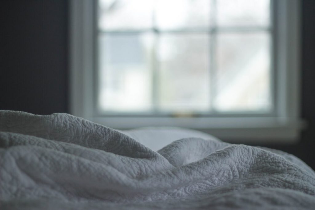 Comfortabel bed met witte lakens voor betere slaap zonder vermoeidheid
