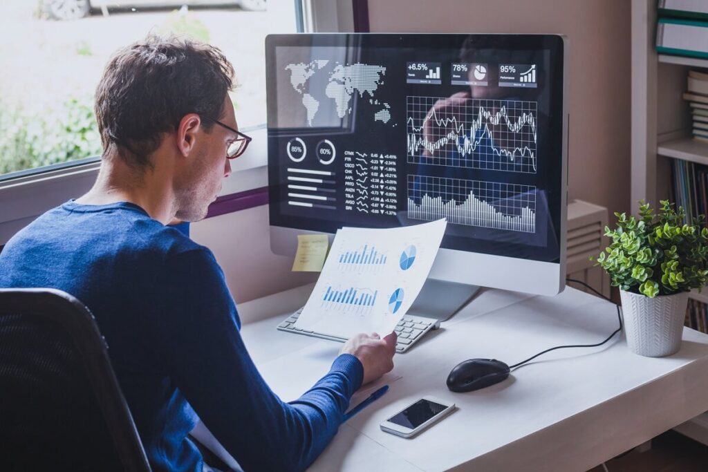 Data analyst die aan een bureau werkt met grafieken en data visualisaties op de monitor om patronen te analyseren