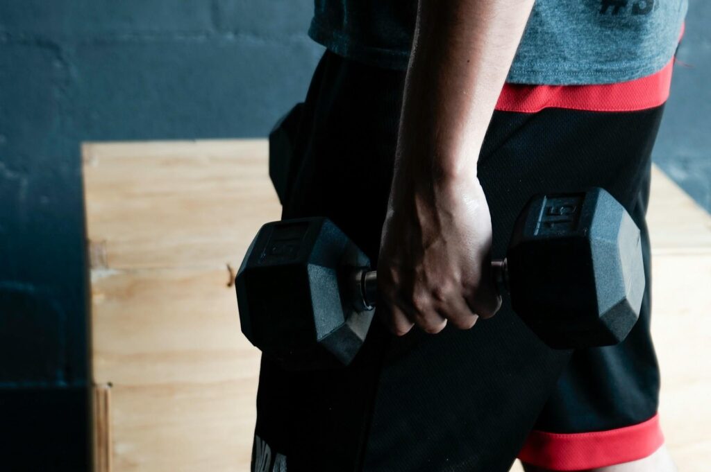 Man voert thuis sporten uit met dumbbells en fitnessapparatuur in moderne trainingsruimte